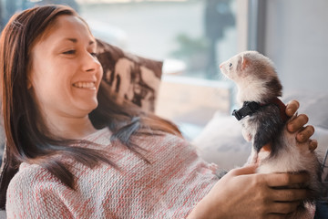 Happy young woman and her pet ferret in cafe