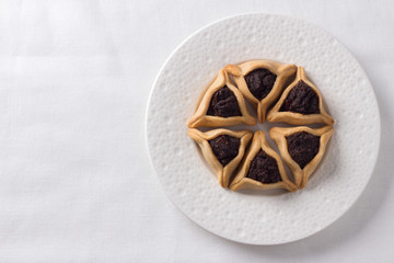 Traditional sweets for Jewish holiday of Purim. Hamantashen cookies or Aman ears, triangular cookies with poppy seeds, top view, free space