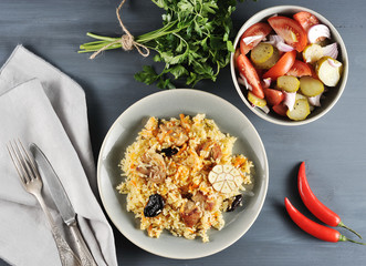 Oriental dish - plov with prunes, salad with onions and pickles, parsley