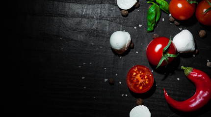 food background. red chili peppers, cherry tomato, basil, black pepper, mozzarella balls, salt on dark wooden background with copy space. top view