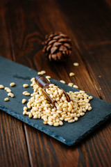 Pine nuts on a black slate with wooden scoop