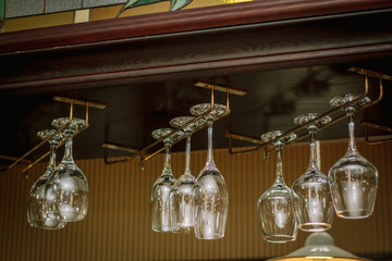 Wine glasses in a bar on wooden rack.