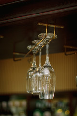 Wine glasses in a bar on wooden rack.