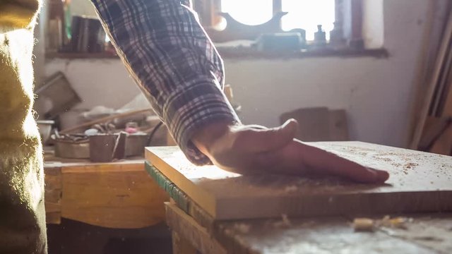 A carpenter who tests the uniformity of a wooden board in the workshop. The concept of the woodworking industry, carpentry, restoration of wooden products