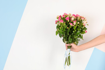 Fototapeta premium Woman with beautiful bouquet of roses on color background