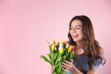 Beautiful woman holding bouquet of tulips on color background