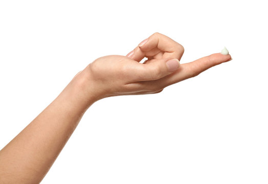 Hand of young woman with cream on finger, against white background