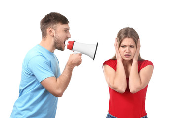 Young man shouting into megaphone at woman on white background. Problems in relationship