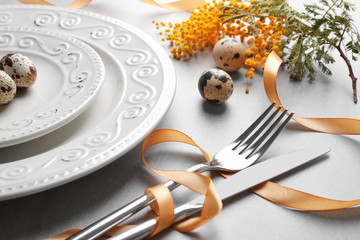 Cutlery with ribbon and quail eggs as decor for Easter table setting, closeup