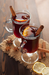 Red mulled wine on burlap on a wooden table with various spices