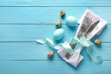 Beautifully decorated cutlery and painted eggs for Easter table setting on wooden background