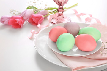Beautiful festive Easter table setting with flowers and painted eggs on white background