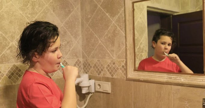 Teen boy  in front of the mirror  brushing his teeth