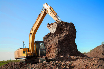 A large construction excavator of yellow color on the construction site in a quarry for quarrying