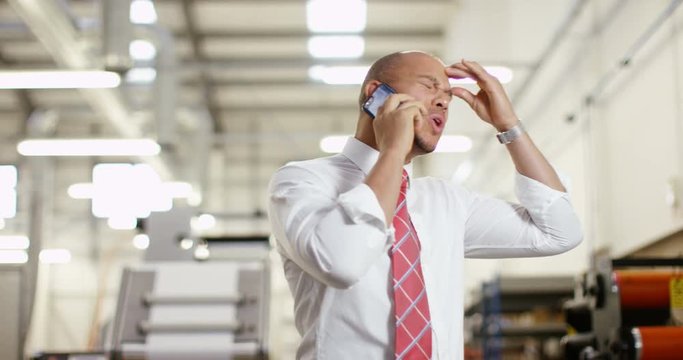 4K Frustrated & annoyed businessman in factory dealing with business problems over the phone