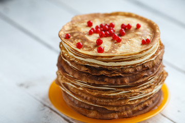 High stack of classic Russian thin pancakes with red currant. Rustic style. Traditional for the Russian pancake week Maslenitsa