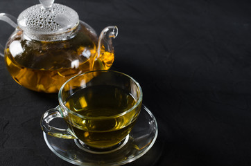 Cup of delicious herbal tea and glass teapot.