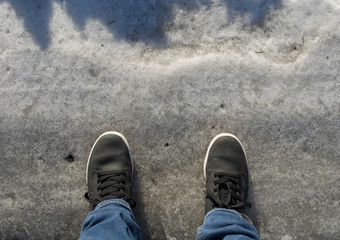 background: pair of black leather shoes, boots, on a city street covered with snow and ice after a winter snowfall, slippery, girl walking, lifestyle, jeans, sun, winter, Italy