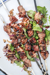 Traditionelle russische Schaschlik Grillspieße   mit Zwiebeln und Salat als Draufsicht  auf einem Teller