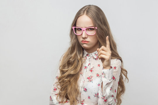Hey! I'm seriously! Warning sign. Teenager girl looking at camera with seriously look and finger up