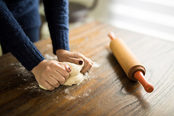 Female hands kneading dough in flour