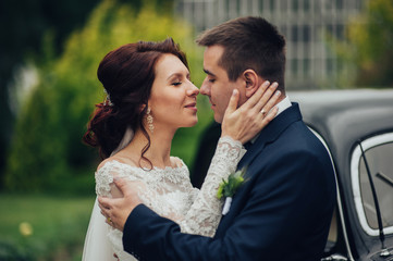 stylish bride and groom sensually posing near retro car with boh