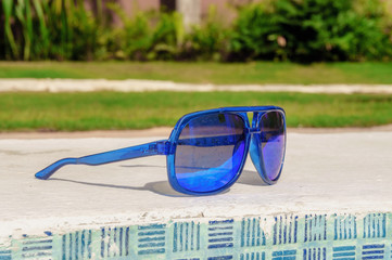 sunglasses closeup on the rim of the pool
