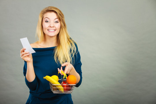 Happy woman holding shopping basket with fruits