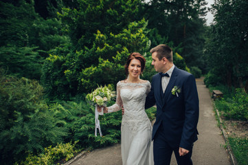 beautiful gorgeous bride and groom walking in sunny park and kis