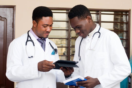 young doctors standing and sharing a tablet.young doctors standing and sharing techniques working on a tablet.