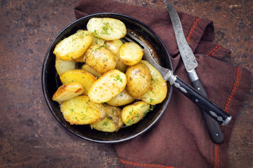 Roast Potatoes with herbs as top view in an iron cast pan