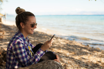 Happy smiling girl on vacation using phone