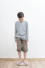 the boy stands on the scale and measures the weight