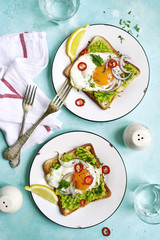 Toast with avocado (guacamole), fried egg and spices for a brakfast.Top view.