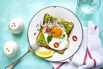 Toast with avocado (guacamole), fried egg and spices for a brakfast.Top view.