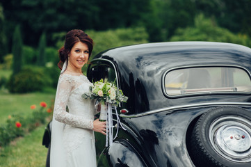 stylish bride and groom sensually posing near retro car with boh