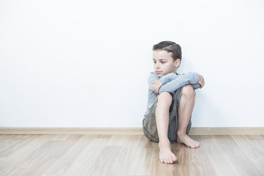 Sad boy sitting lonely in the room.Isolated on the white background