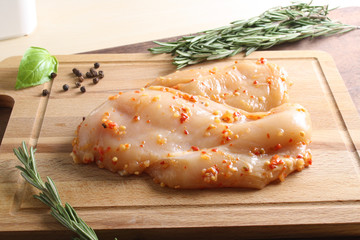 chicken breast in marinade spice, board, rosemary