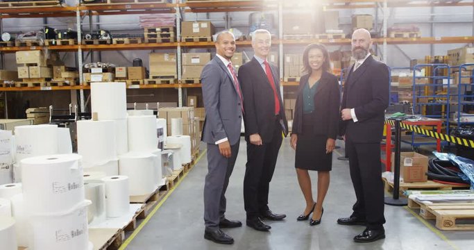 4K Portrait smiling business team in suits chatting in large warehouse