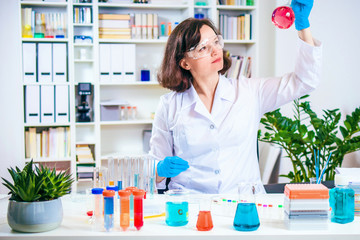 Scientist or researcher looks at the reagent flask. Laboratory workbench with colored chemical reagents in laboratory jars and test tubes.