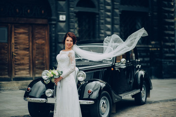 stylish bride and groom sensually posing near retro car with boh