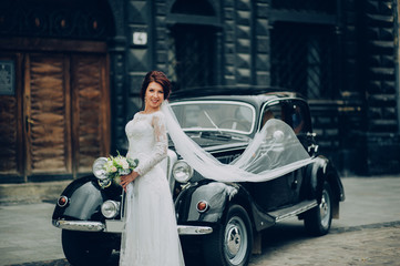 stylish bride and groom sensually posing near retro car with boh