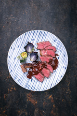 Barbecue wagyu aged fillet steak slices with brownie and chili chocolate sauce as top view on a plate