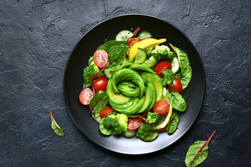 Vegetable salad with avocado, cucumber, cherry tomato, chard leaves and broccoli.Top view with copy space.