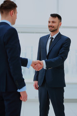 Business colleagues sitting at a table during a meeting with two male executives shaking hands.