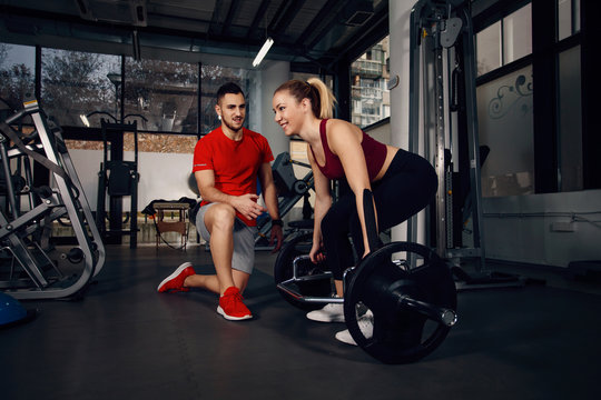 Girl exercising in the gym with assistance of personal trainer