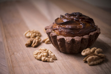Chocolate muffin cupcake with nuts on wood background