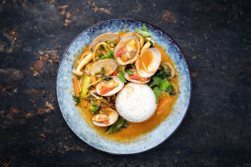 Traditional Thai kaeng phet red curry with clams and rice as top view on a plate