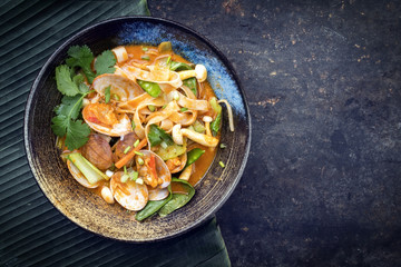 Obraz na płótnie Canvas Traditional Thai kaeng phet red curry with clams and vegetable as top view in a bowl with copy space right