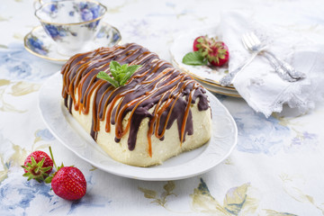 Traditional chocolate caramel cheesecake with fresh strawberries as top view on a plate